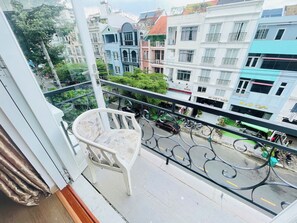 A balcony with a chair, overlooking a street with buildings and parked cars. - Diamond Suite Apartment (Ho Chi Minh City)