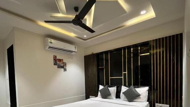 Ein modernes Schlafzimmer mit einem großen Bett, Deckenventilator, Klimaanlage und einem dunkel gestreiften Kleiderschrank.