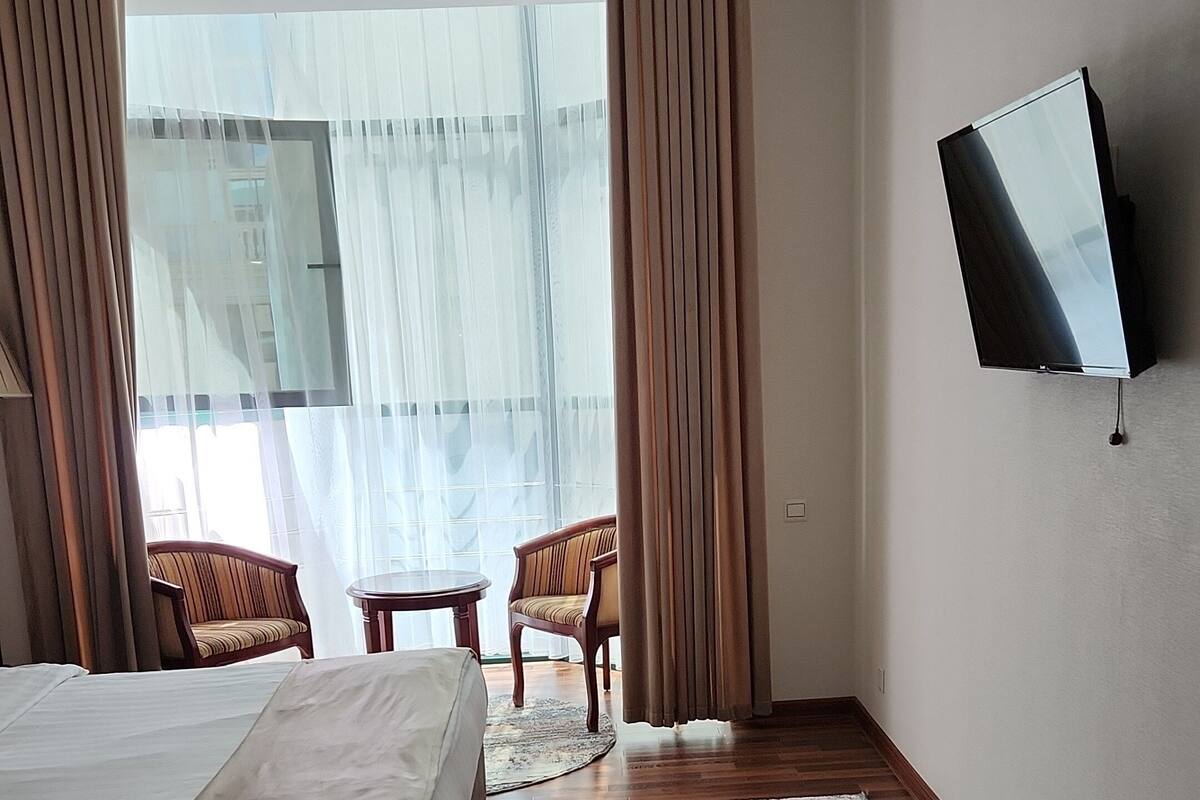 A hotel room with a bed, a desk, a television, and a view of the outdoors.