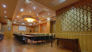 Un salón de conferencias con una larga mesa, sillas y una pantalla de proyector.