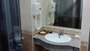 Un baño con cabina de ducha de vidrio, un lavabo con espejo y un perchero para toallas.