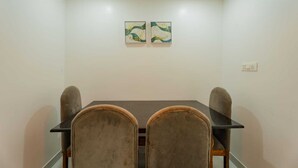 A conference room with a rectangular table and four chairs. There are two wall-mounted artworks above the table. - New White Minar  (Calangute)