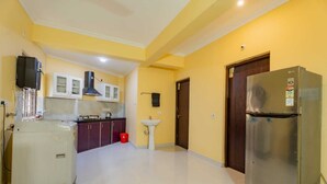 A kitchen with a refrigerator, sink, and cabinets. - New White Minar  (Calangute)