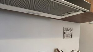 A kitchen with a built-in induction cooktop, a dish rack with utensils, and a wall-mounted sign.