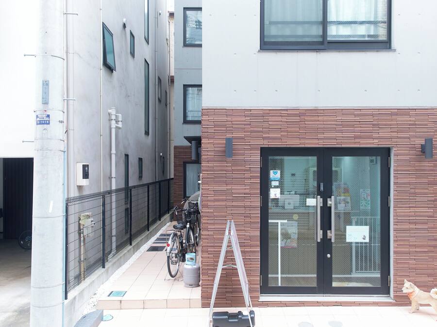 Un edificio con puerta de entrada de vidrio, fachada de ladrillo y una valla metálica.