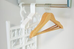 Un cintre en bois et un cintre en plastique blanc, tous deux fixés sur une tige métallique.