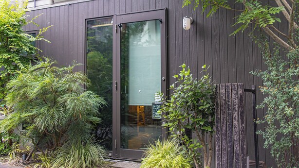 A modern building with a dark exterior, large glass doors, and a small balcony with a railing. - Ars Garden Omori (Tokyo)