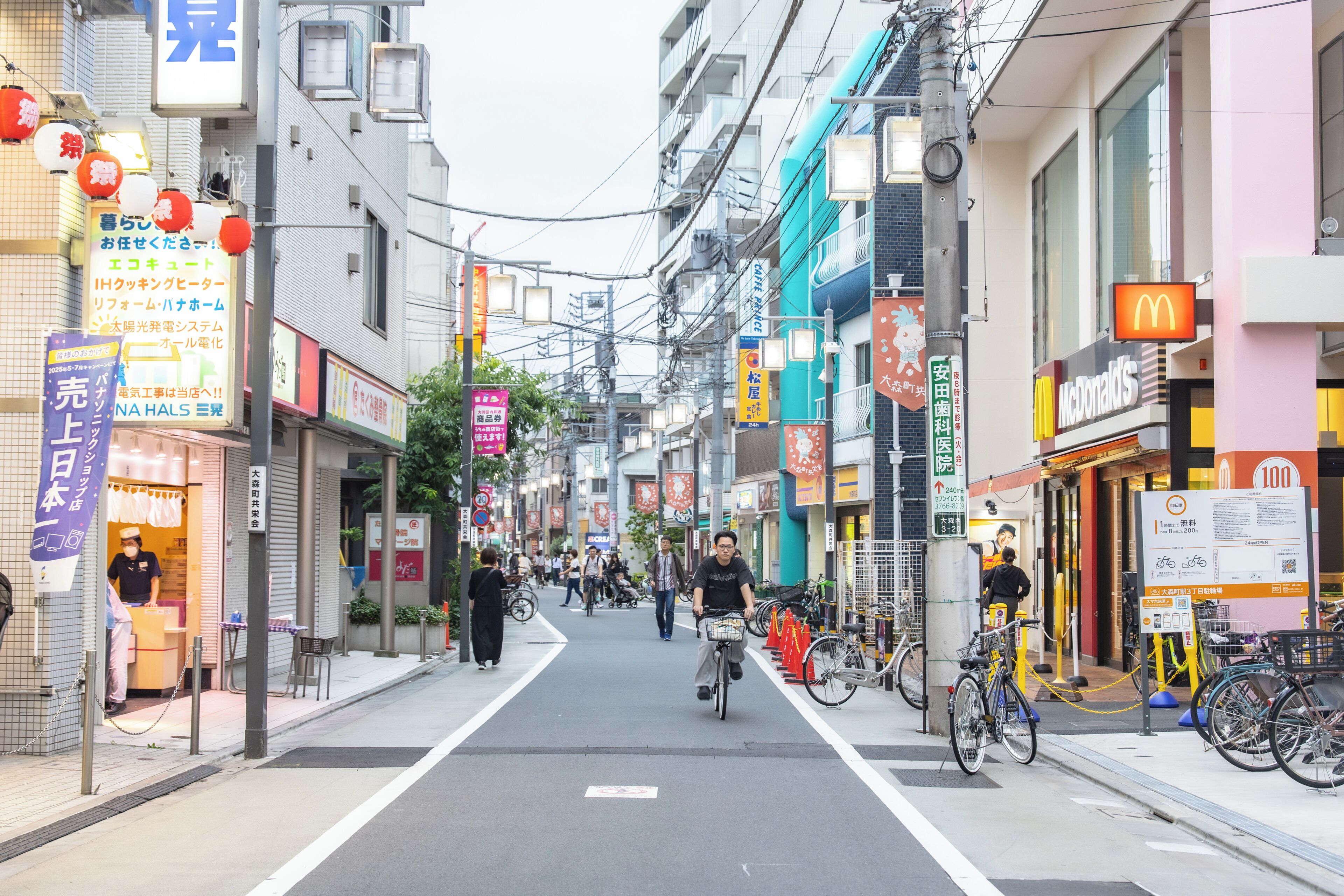 Una calle con bicicletas, peatones y diversas tiendas, incluyendo un McDonald's.