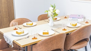 A dining table with plates of cake, a vase with flowers, and a book titled 'LONDON' on the table. - Ars Garden Omori (Tokyo)