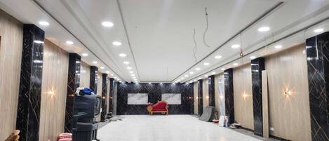Um quarto amplo com piso de mármore, um sofá vermelho e um espelho grande na parede.