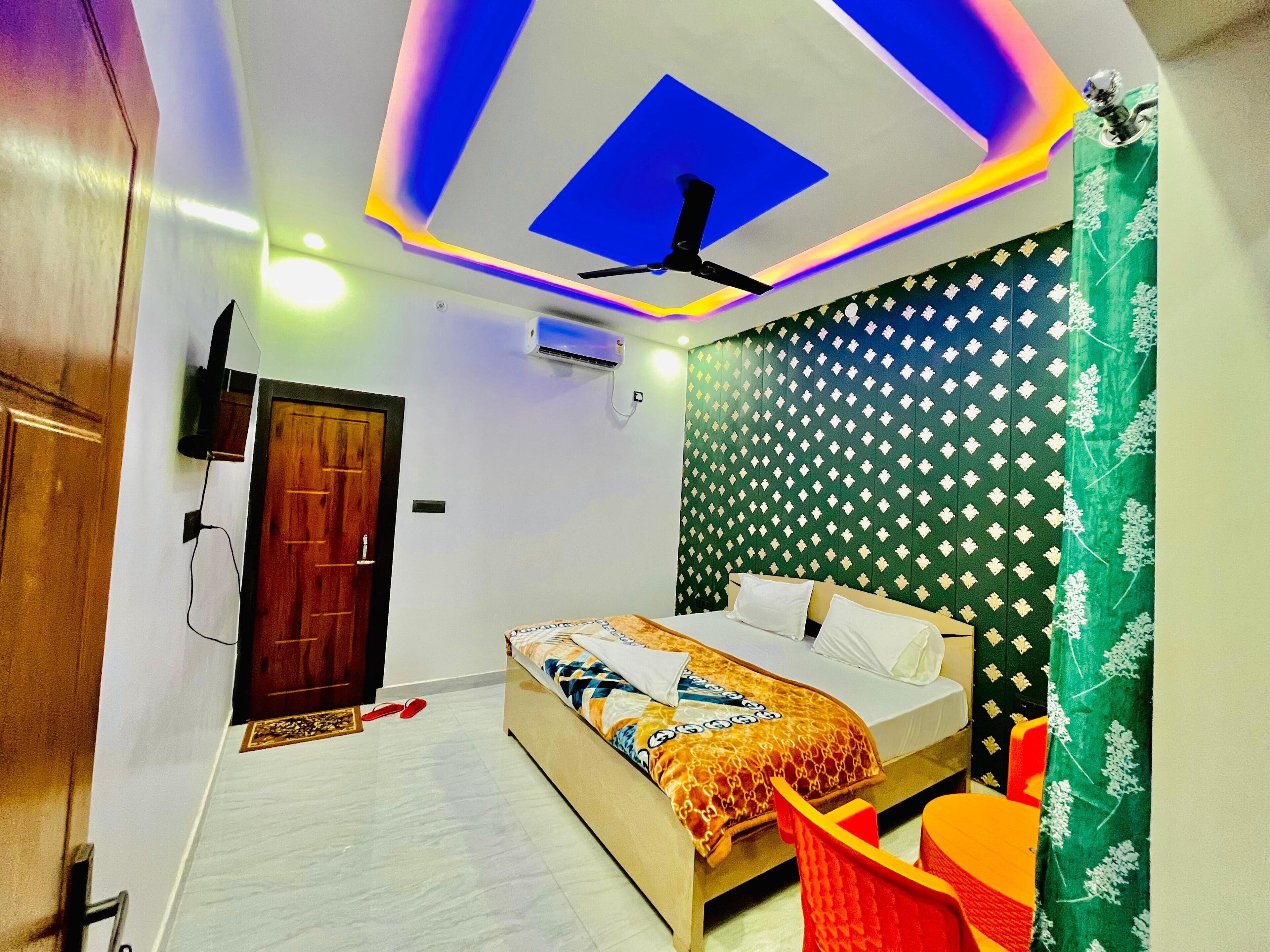 Un dormitorio con cama, ventilador de techo, aire acondicionado de pared y cortina estampada.