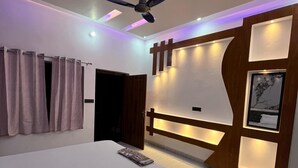 Een moderne slaapkamer met een groot bed, een plafondventilator en een tv aan de muur.