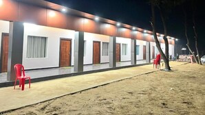 Een gebouw met meerdere kamers, elk met een deur en ramen, en een geplaveid pad ervoor.