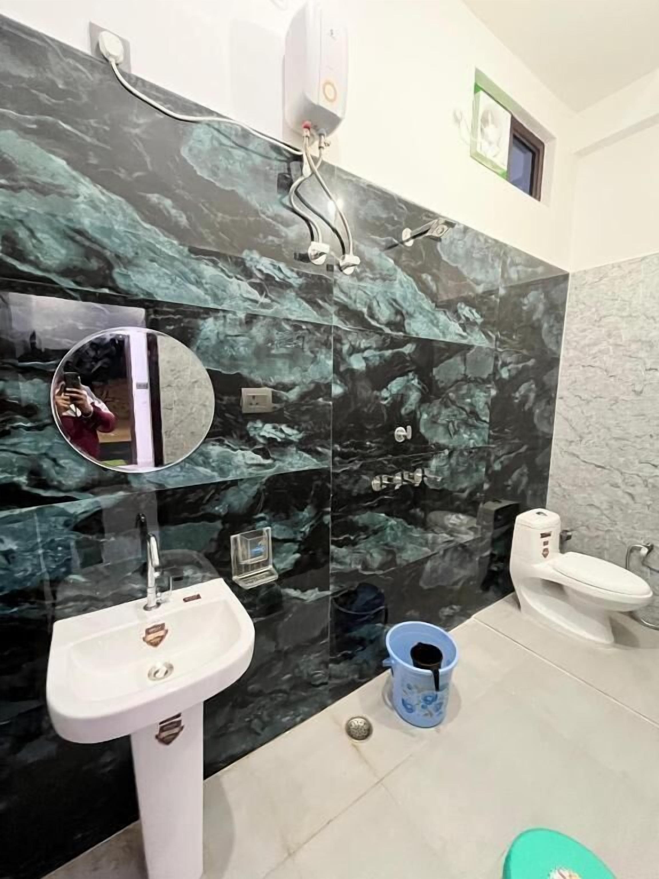 A bathroom with a white sink, a mirror, a toilet, and a shower.