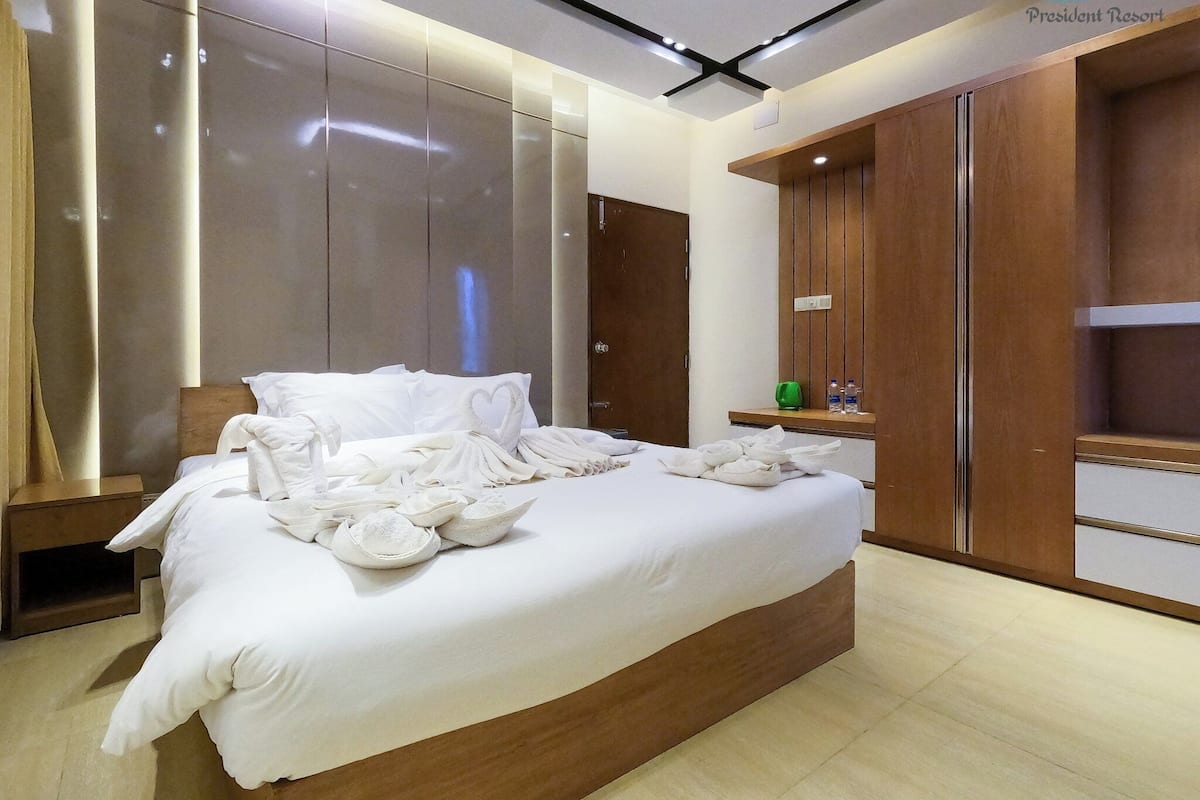 Ein modernes Hotelzimmer mit einem großen Bett, einem Holzschrank und einem Nachttisch mit Toilettenartikeln.