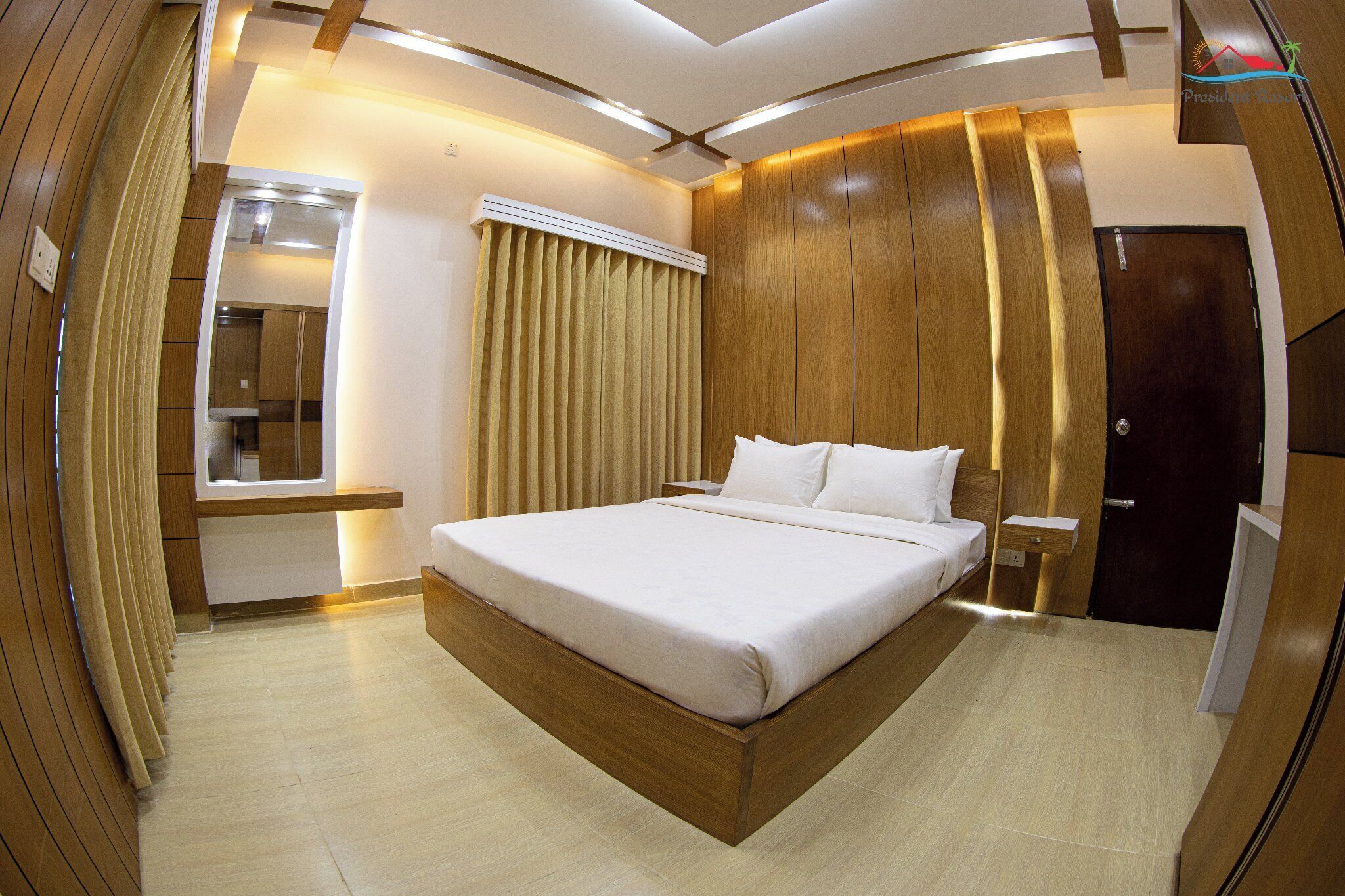 A modern hotel room with a large bed, wooden paneling, a built-in wardrobe, and a mirror.