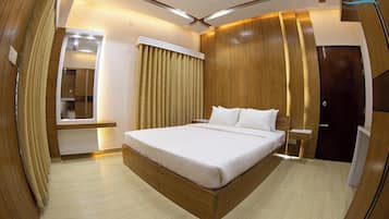 A modern hotel room with a large bed, wooden paneling, a built-in wardrobe, and a mirror.