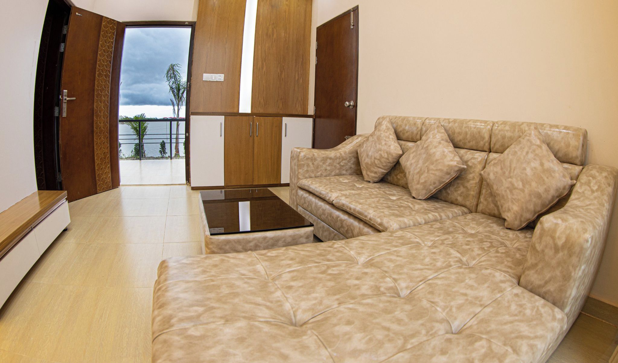 A spacious living area with a beige sofa, a coffee table, and wooden cabinets.