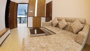 A spacious living area with a beige sofa, a coffee table, and wooden cabinets. - President Resort Kishoreganj (Mithamain)