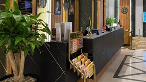 A modern reception area with a black marble counter, wooden accents, and a potted plant. - SWAT SERVICED APARTMENTS 5 (Al Khobar)