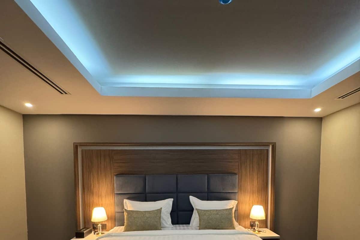 Ein Hotelzimmer mit einem großen Bett, zwei Nachttischen mit Lampen, einem dunklen Kopfteil und einem Dachfenster.