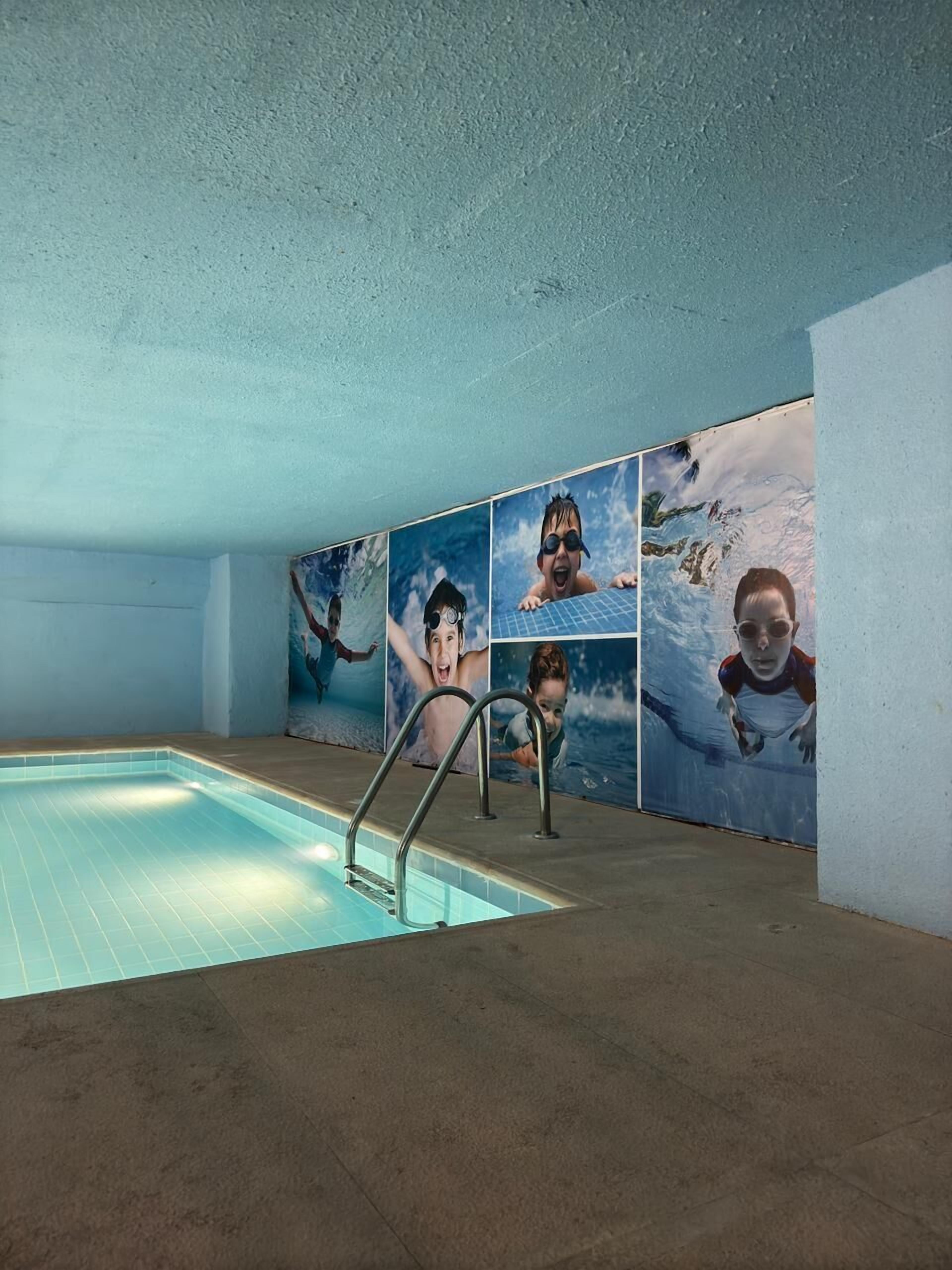 A swimming pool with a tiled floor and a metal ladder.