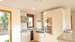 Una cocina moderna con armarios blancos, electrodomésticos de acero inoxidable y encimera de granito.