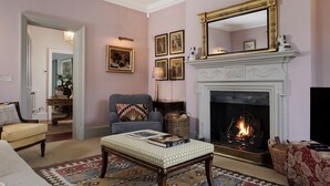 A living room with a fireplace, a sofa, a chair, and a patterned rug. - Elegant dog friendly home with panoramic views - The Old Vicarage (Aldsworth)