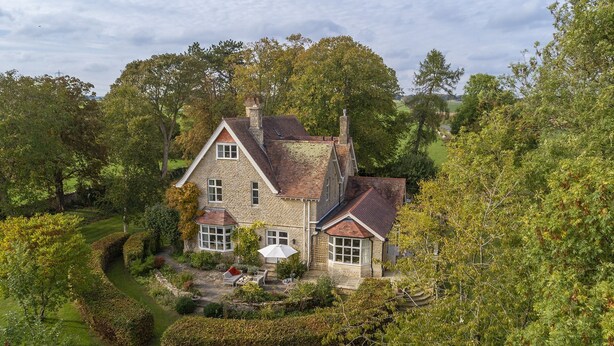 A large stone house with a traditional design, surrounded by lush greenery and a well-maintained garden. - Elegant dog friendly home with panoramic views - The Old Vicarage (Aldsworth)