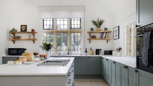 A modern kitchen with a central island, built-in appliances, and ample natural light from large windows. - Incredible dog friendly with hot tub - The Old Stores (Toddington)
