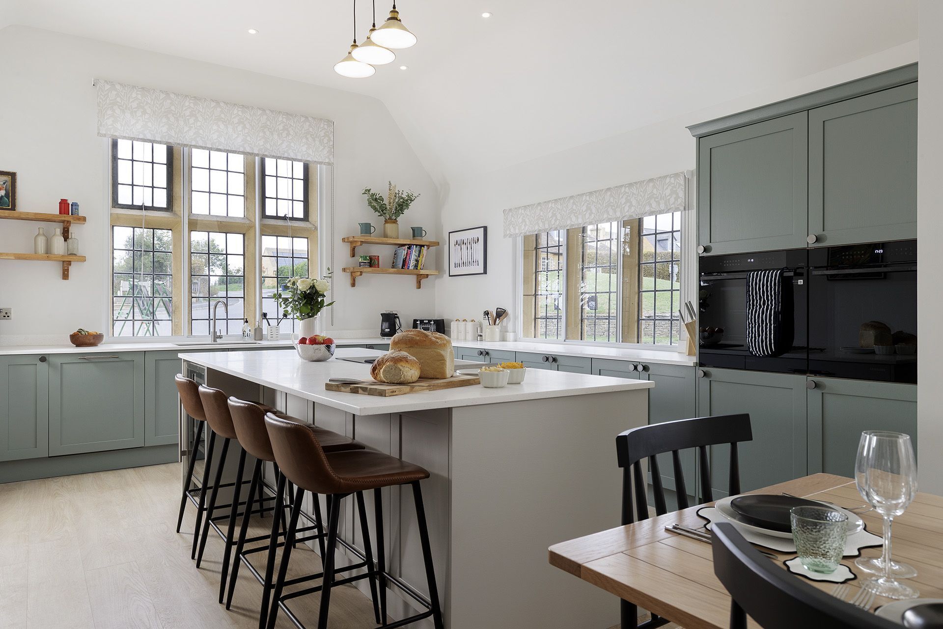 A modern kitchen with a large island, bar stools, and a dining table set for two.