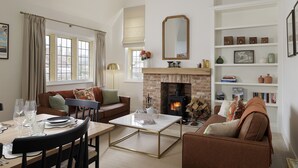 A living room with a fireplace, a sofa, a coffee table, and a bookshelf. - Incredible dog friendly with hot tub - The Old Stores (Toddington)
