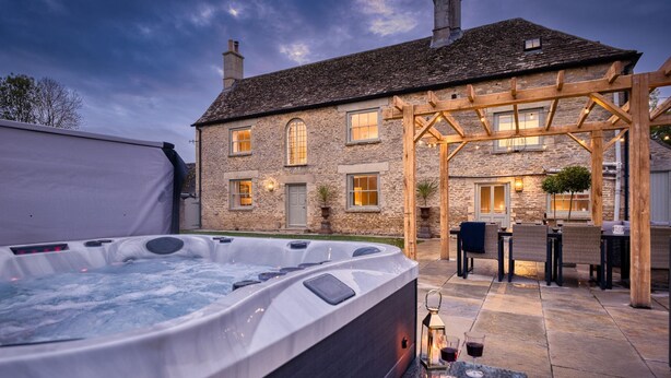 Edificio de piedra con jacuzzi y zona de estar al aire libre.