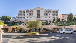 A multi-story hotel with a central courtyard, a parking area, and a sign indicating a parking fee. - Bright 1-bedroom sea & mountain view min. from beach (Cannes)