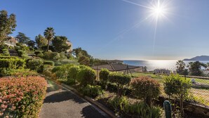 A coastal residential area with a clear view of the sea, a paved pathway, and well-maintained gardens. - Bright 1-bedroom sea & mountain view min. from beach (Cannes)