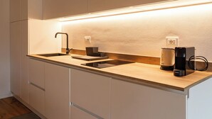 Una cocina moderna con un lavaplatos empotrado, una cafetera y un hervidor sobre la encimera.