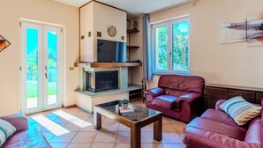 Ein Wohnzimmer mit Kamin, Ledersofas, einem Glastisch und einem Fernseher.