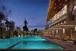 A swimming pool with lounge chairs and a building with a stone facade.