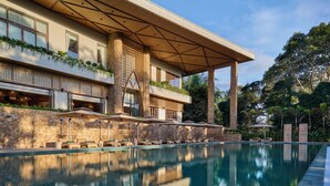 Ein modernes Hotel mit großem Pool, Außenbereich zum Sitzen und einer überdachten Terrasse.
