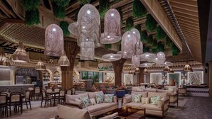 Eine großzügige Lobby mit hängenden Pendelleuchten, bequemen Sitzgelegenheiten und einer Bar.