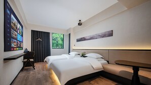 Moderni hotellihuone, jossa on kaksi sänkyä, työpöytä ja oleskelualue.