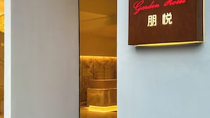Hotellin sisäänkäynti, jossa on kyltti, jossa lukee ”Garden Hotel”, sekä vastaanottoalue marmoritiskillä.