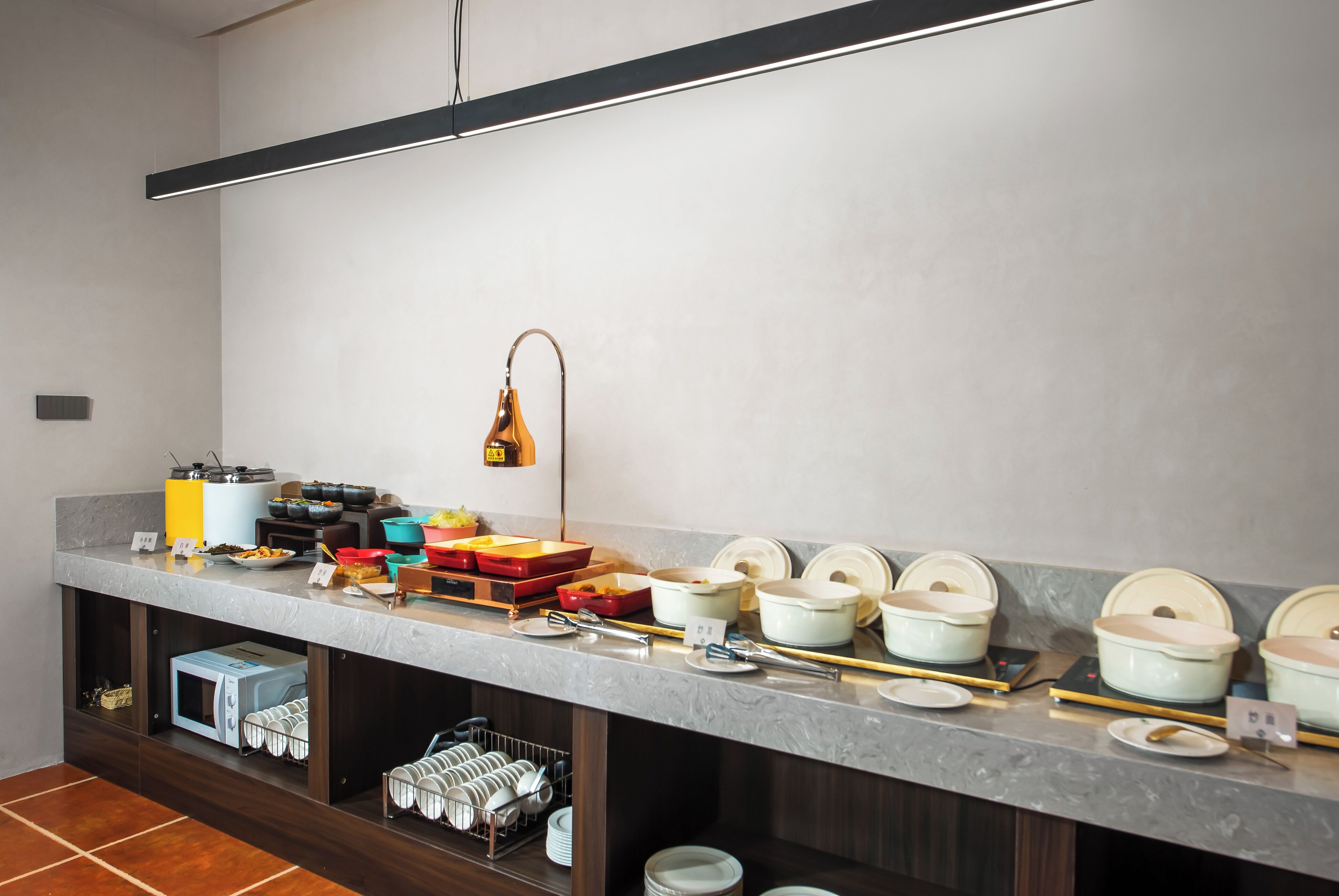 A buffet setup with various food containers and utensils, a microwave, and a dish rack.