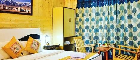 A wooden-themed room with a bed, a chair, a small table, and a mirror.