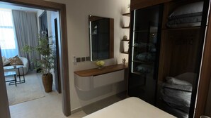 Een moderne slaapkamer met een groot bed, een houten kaptafel, een spiegel en een inloopkast.