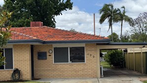 A single-story house with a red-tiled roof, brick exterior, and a covered porch.