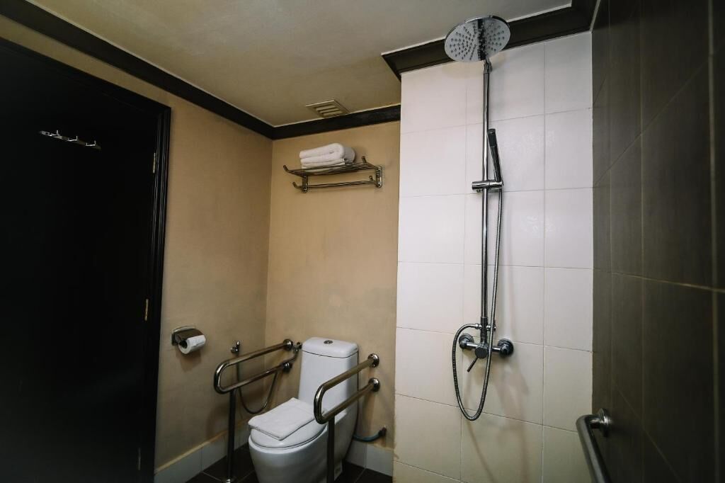 A bathroom with a toilet, a shower, and a towel rack.
