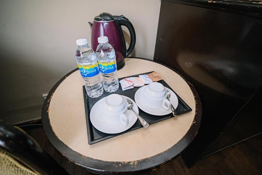 A small round table with a tray containing two water bottles, two white cups, and a spoon.
