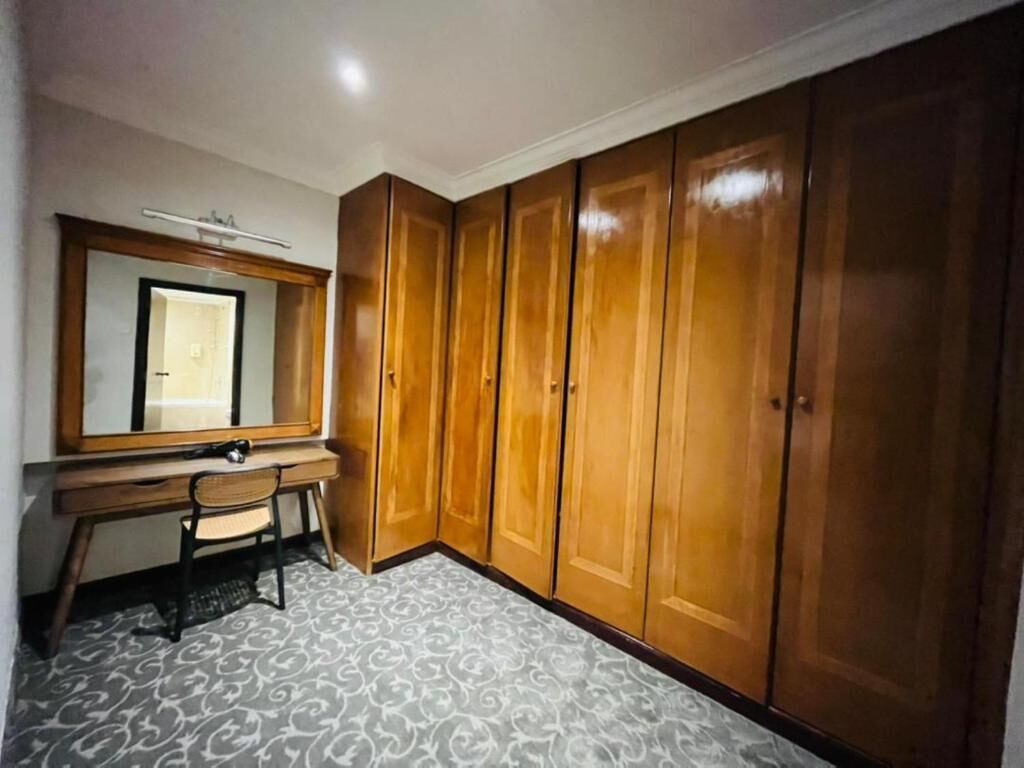 Una camera da letto con un armadio in legno, una scrivania con una sedia e una tappeto decorato.