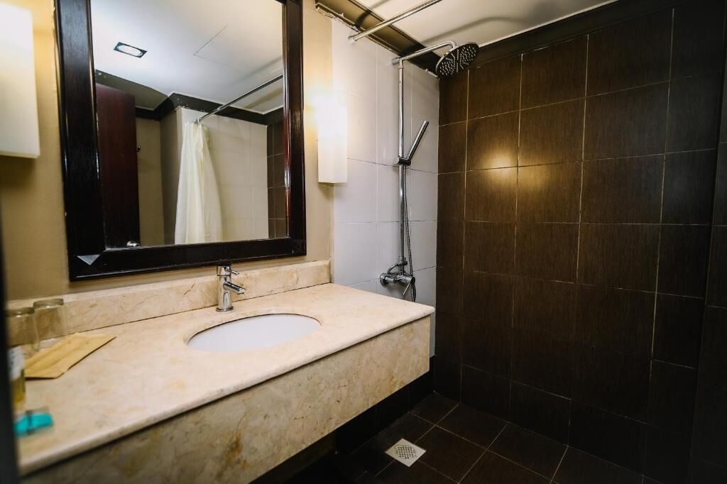 A bathroom with a sink, mirror, and shower.